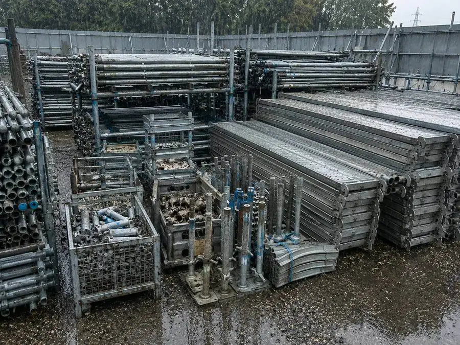 現場の隅に積まれた余り資材・雨ざらしの足場材